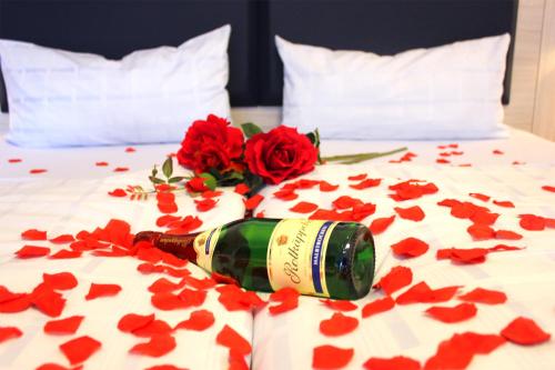 a bottle of champagne laying on a bed with red hearts at Hotel Altenwerder Hof in Hamburg