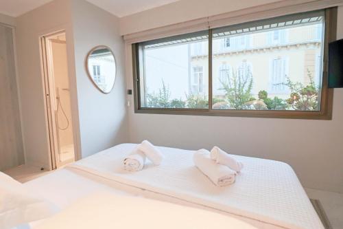 une chambre avec un lit blanc avec des serviettes dessus dans l'établissement GRAY Renovated luxurious apartment located in Cannes, à Cannes