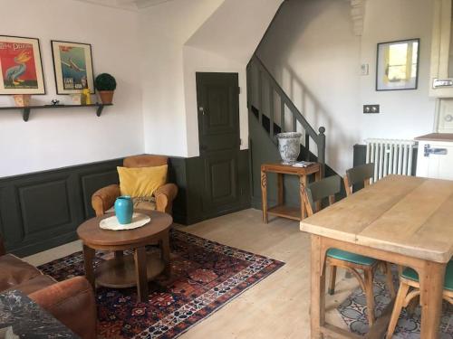 un salon avec une table et des chaises et un escalier dans l'établissement LE CHARMANT COLIBRI ÉTRETAT, à Étretat
