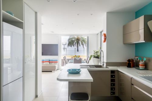 une cuisine avec des comptoirs blancs et un salon dans l'établissement PLAGE Ground floor apartment on seafront with large terrace, à Cannes