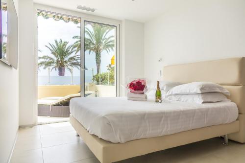 - une chambre blanche avec un lit et une fenêtre bordée de palmiers dans l'établissement PLAGE Ground floor apartment on seafront with large terrace, à Cannes