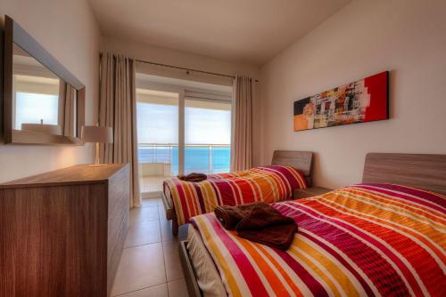 two beds in a room with a view of the ocean at SEAFRONT LUXURY APARTMENT incl POOL in Sliema