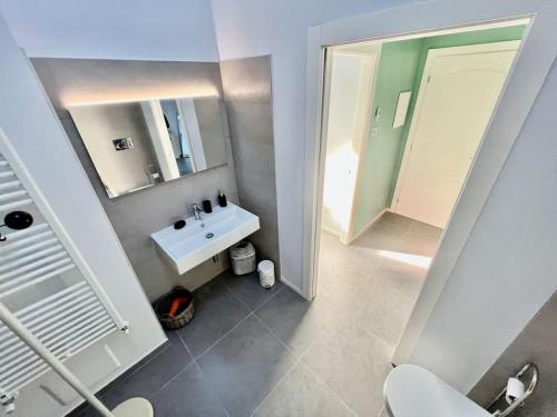 een badkamer met een witte wastafel en een spiegel bij Prestigioso attico a passo Duomo by Revenue House in Casale Monferrato
