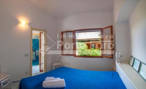 um quarto com uma cama azul e uma janela em 24PN - Vecchio Marino splendido villino vista mare em Palau