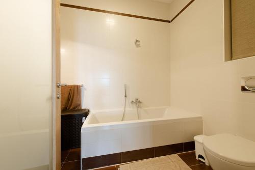 ein weißes Bad mit einer Badewanne und einem WC in der Unterkunft Seafront Luxury Apartment with Pool in Sliema