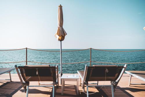 two chairs and an umbrella on the deck of a boat at Tre Merli Beach Hotel in Trieste