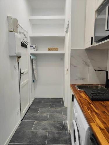 une cuisine avec des armoires blanches et un sol carrelé dans l'établissement Charmant appartement hyper centre métro gare, à Toulouse