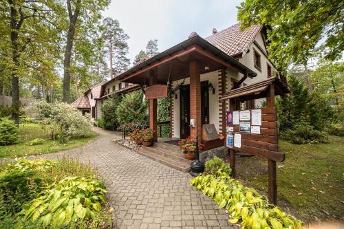 um pequeno edifício com uma placa em frente em Ośrodek Wrzosowa Góra - domki em Ruciane-Nida