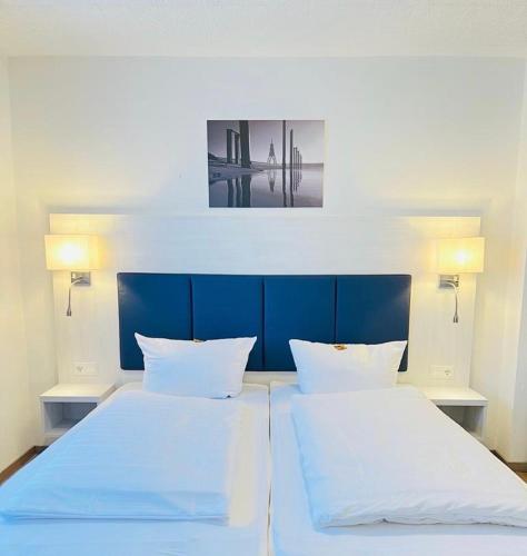 a bedroom with two white beds and a blue headboard at Haus zur Heimat in Cuxhaven