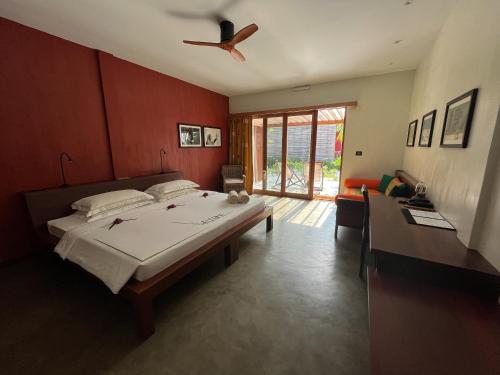 a bedroom with a large bed and a ceiling fan at The Barefoot Eco Hotel in Hanimaadhoo