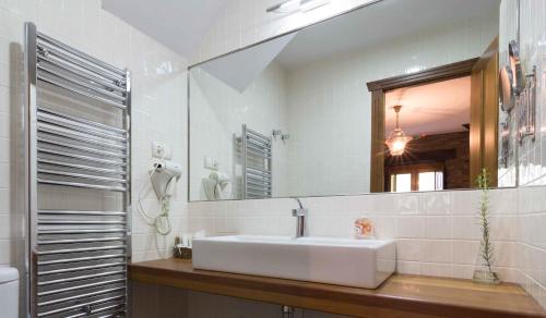 Baño blanco con lavabo y espejo en Apartamentos Rurales Sierra en Palacio de Naviego