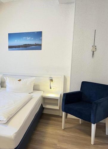 a bedroom with a bed and a blue chair at Haus zur Heimat in Cuxhaven