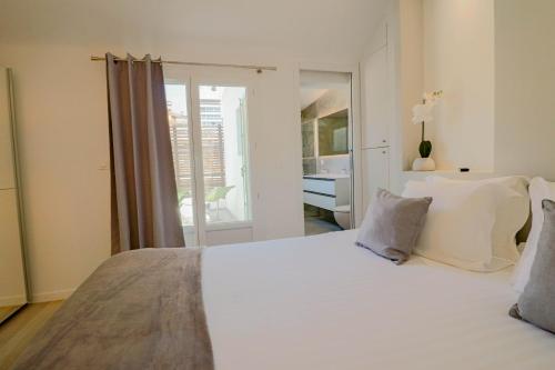 un lit blanc dans une chambre avec une fenêtre dans l'établissement MEYNADIER Renovated designer apartment with rooftop in Cannes, à Cannes