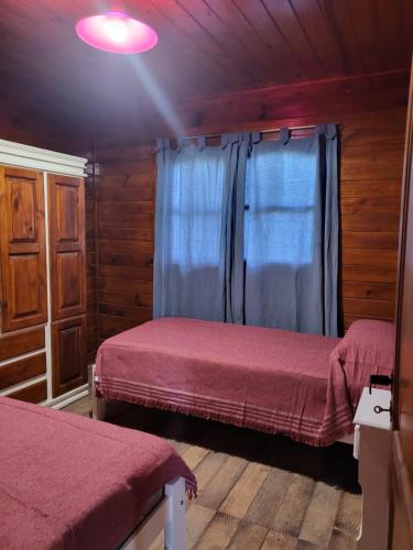 1 Schlafzimmer mit 2 Betten in einem Holzhaus in der Unterkunft Cabaña Los Acacios II Lobos in Lobos