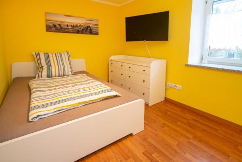 una camera da letto con pareti gialle, un letto e un comò di Apartment - Wohnung Memmingen Nr. 1 a Memmingen