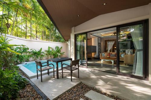 a patio with a table and chairs next to a pool at Dewa Phuket Resort & Villas, Nai Yang Beach in Nai Yang Beach