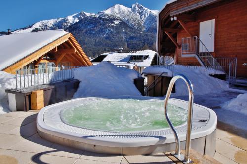 a hot tub on a patio with snow covered mountains at Mountains Hotel in Seefeld in Tirol