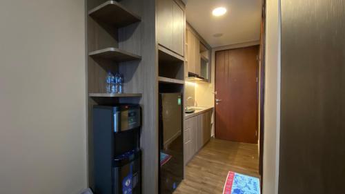 a small kitchen with a refrigerator in a room at Meisterstadt Pollux Habibie Apartment by uhomeid in Batam Center