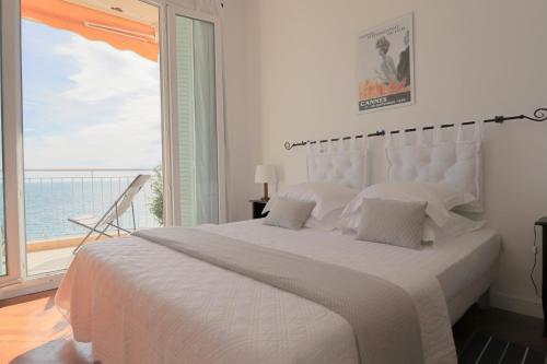 - une chambre blanche avec un grand lit et une grande fenêtre dans l'établissement ROOFTOP DE LA PLAGE Charming apartment on seafront with superb roof terrace, à Cannes