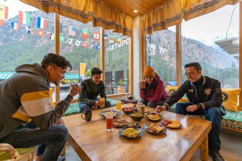 un grupo de personas sentadas alrededor de una mesa comiendo comida en The Hosteller Kasol, Parvati Valley en Kasol