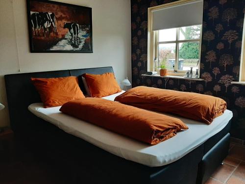 a bed with orange pillows on it in a room at De Hörst in Rossum