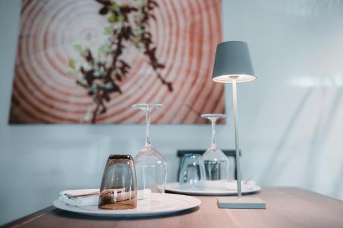 two wine glasses and a lamp on a table at Tre Merli Beach Hotel in Trieste