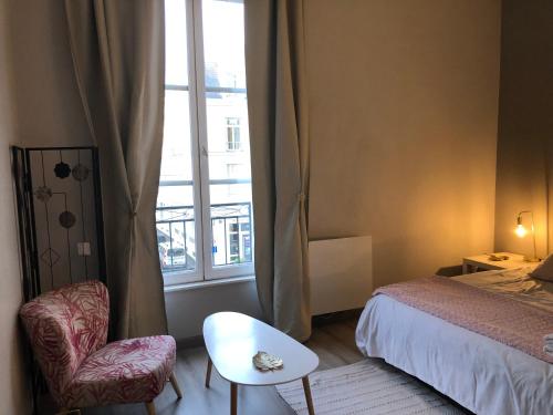 a bedroom with a bed and a chair and a window at Bel appartement spacieux et lumineux hyper centre Blois in Blois