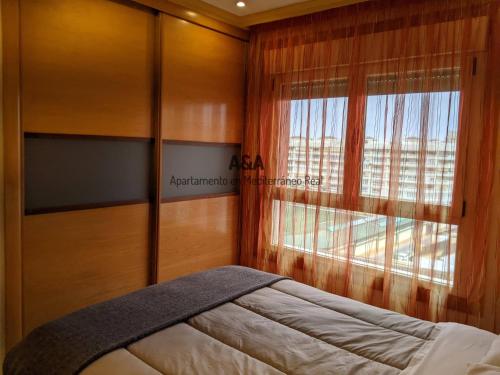 フエンヒロラにあるApartamento En Mediterráneo Real, Los Boliches, Fuengirolaのベッドルーム1室(ベッド1台、大きな窓付)