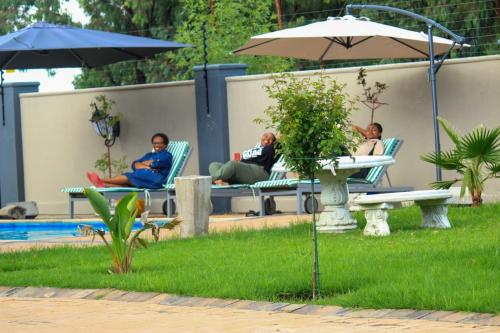 a group of people sitting in lawn chairs by a pool at Tranquility Guesthouse in Standerton