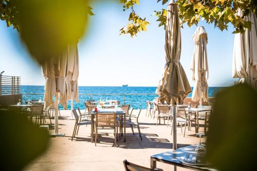 a restaurant with tables and umbrellas on the beach at Tre Merli Beach Hotel in Trieste
