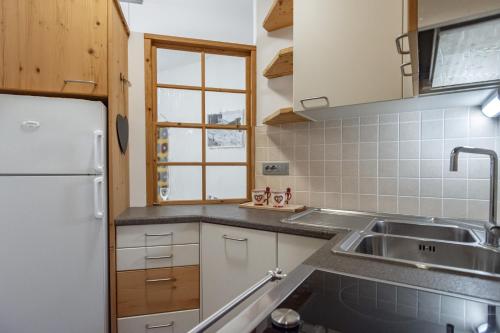 cocina con fregadero y nevera en DolomiApartments - Appartamento Orso Bruno, en Predazzo