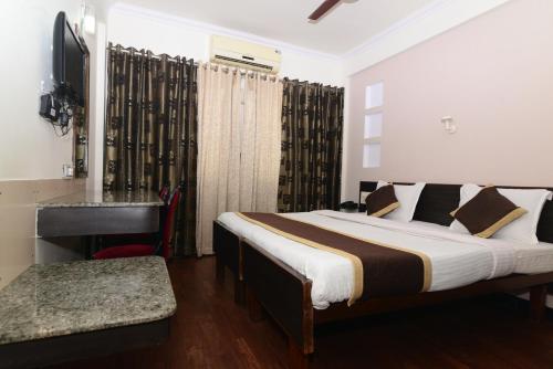 a bedroom with a bed and a desk and a television at Hotel Hanuman in Mangalore