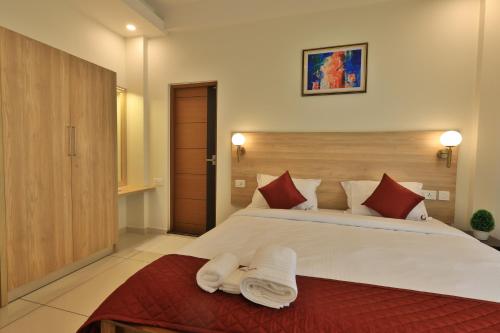 a bedroom with a large white bed with red pillows at Castle Brook Residential Homestay in Thiruvalla