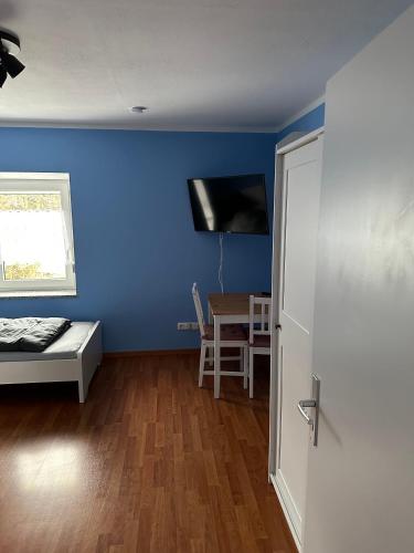 Zimmer mit einer blauen Wand, einem Bett und einem Tisch in der Unterkunft Apartment - Wohnung Memmingen Nr. 3 in Memmingen