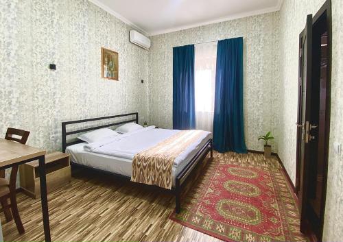 a bedroom with a bed with blue curtains and a table at Zahid Inn in Tashkent