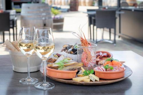 einen Teller mit Speisen und Weingläsern auf dem Tisch in der Unterkunft Wine-Barrel Rivaner in Dreischor