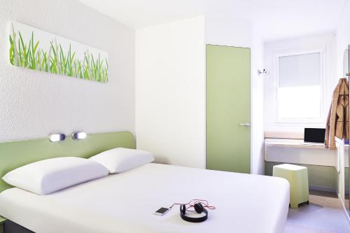 um quarto com uma cama branca e uma parede verde em Ibis Budget Manosque Cadarache em Manosque