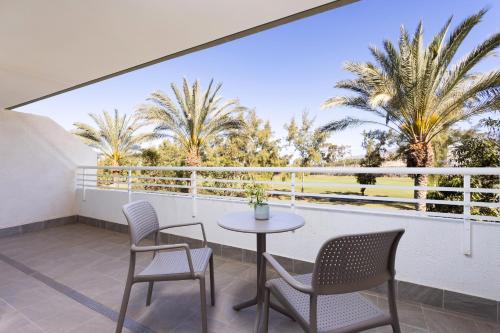 a balcony with a table and chairs and palm trees at Gara Suites Golf & Spa in Playa de las Americas