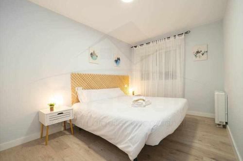 a white bedroom with a large bed and a night stand at Cruz Victoria By Silastur in Gijón