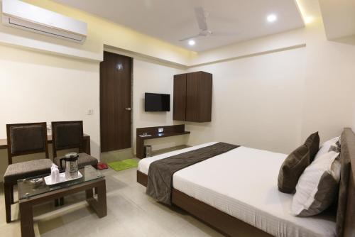 a bedroom with a bed and a desk and a tv at Hotel Luxura, Ahmedabad in Ahmedabad
