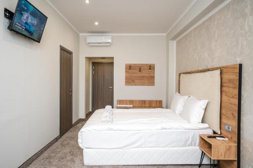 - une chambre avec un grand lit blanc et une télévision dans l'établissement Hotel CITY Sandanski, à Sandanski