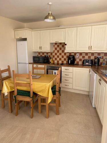 a kitchen with a table and chairs and a refrigerator at Glengesh Court. Ardara town centre. in Ardara