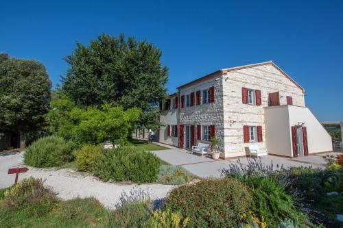an old stone building with red shutters and a tree at Agromarino in Sirolo