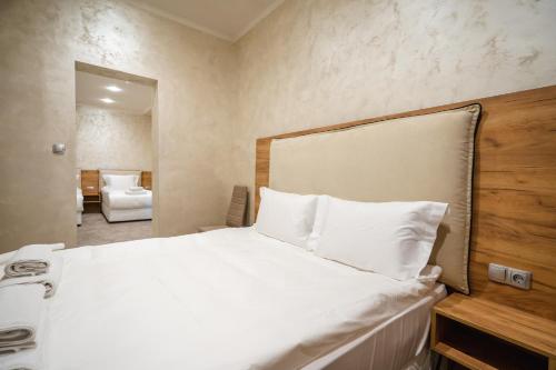 a bedroom with a bed with white sheets and a mirror at Hotel CITY Sandanski in Sandanski