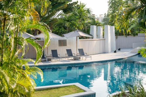 a swimming pool with chairs and palm trees next to it at Dewa Phuket Resort & Villas, Nai Yang Beach in Nai Yang Beach