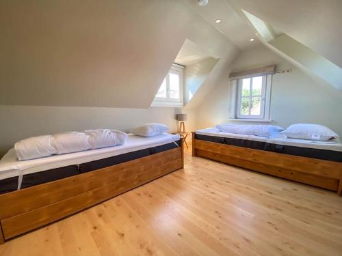 2 Betten in einem Zimmer mit Holzböden und Fenstern in der Unterkunft Villa Trianon -Summer beachhouse in De Panne
