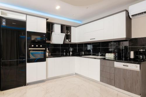 a kitchen with white cabinets and black appliances at Rua Mat - Serene Villas with Modern Comfort, by ZanteWize in Alykes