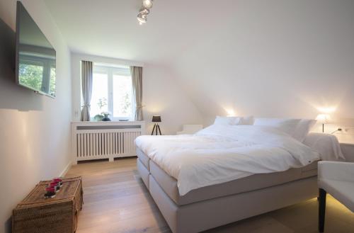 Un dormitorio con una gran cama blanca y una ventana en B&B Patrijzenhoek en Knokke-Heist