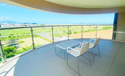 a balcony with a glass table and chairs on it at Holiday Inn Mauritius Mon Trésor by IHG in Blue Bay
