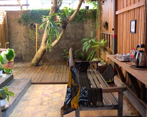 a patio with a wooden bench with a blanket on it at Jogja ethnic house in Yogyakarta